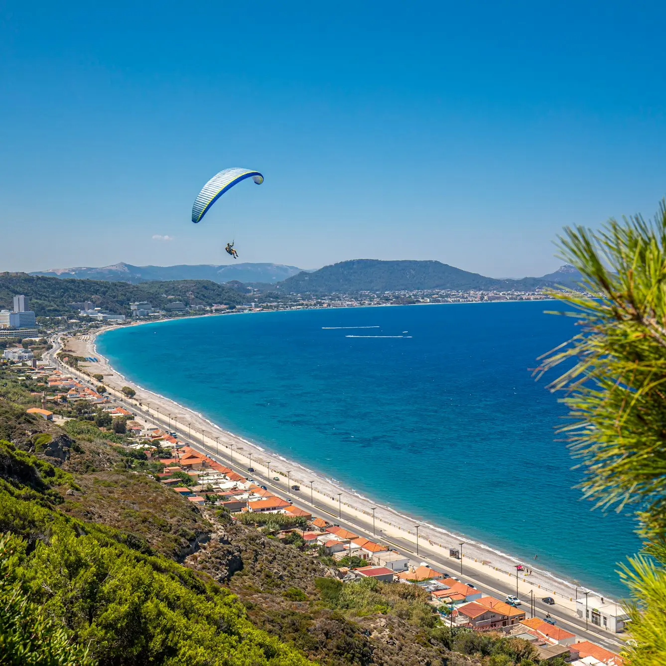 a paraglider flying over a beach next to the ocean