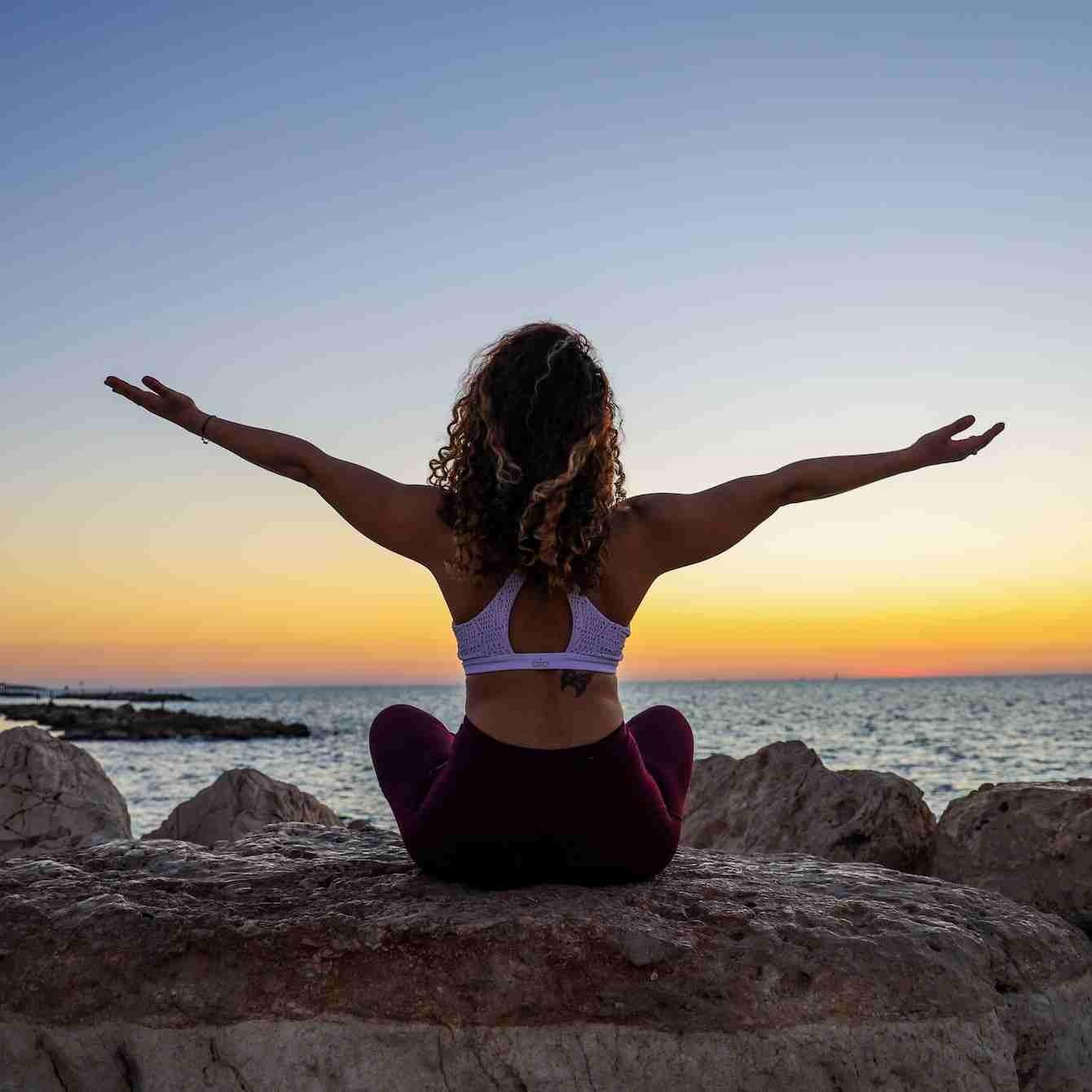 woman sitting on the stone in front of the ocean