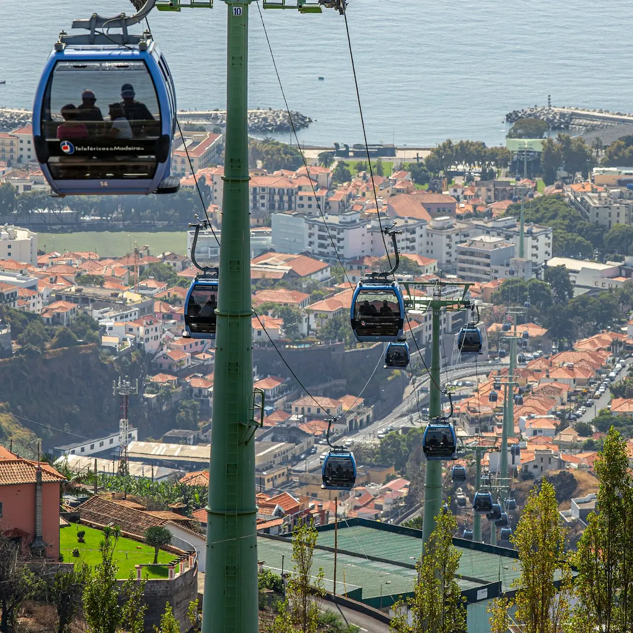 a couple of people riding a ski lift over a city