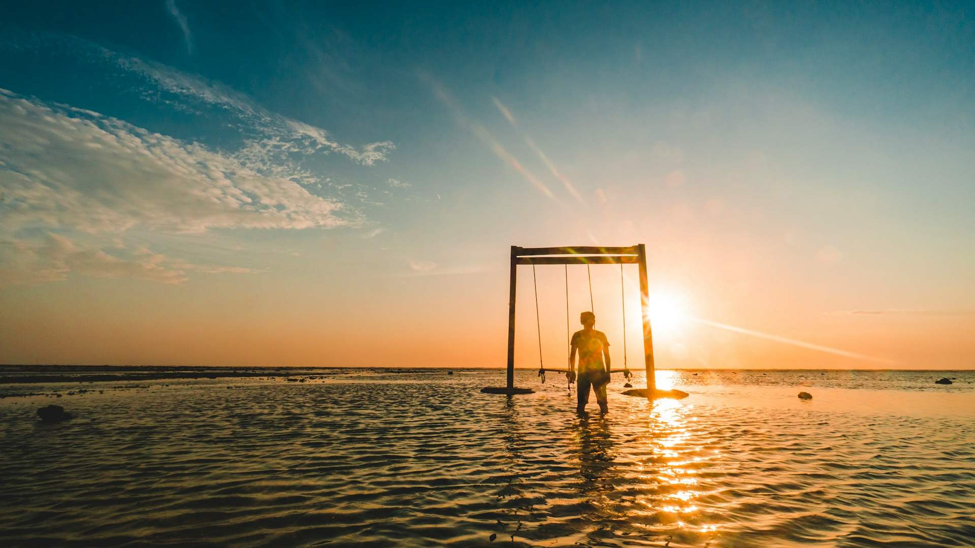 person standing near swing on body of water